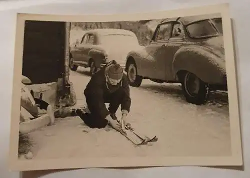 Mann im Schnee mit Ski bei Autos