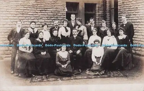R695176 Gruppenfoto. Frauen und Männer sitzen vor dem Haus