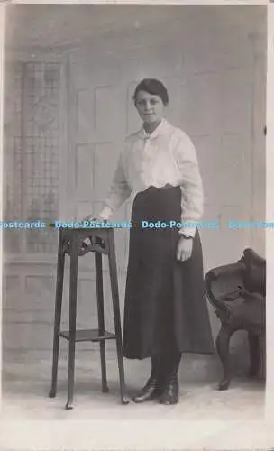 R697515 Frau in langem Rock und Bluse stehend am Tisch. 1918