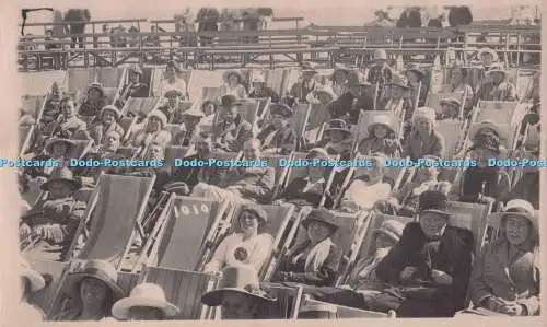 R702321 Männer und Frauen sitzen auf Liegestühlen am Strand. Postkarte