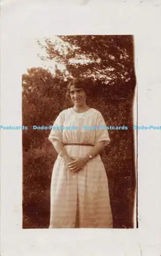 R313888 Frau mit hellen Kleidern im Garten stehend Postkarte