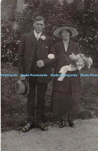 R321567 Hochzeit Frau mit Hut und Blumen in den Händen Ein Mann im Anzug und einem Hut wi