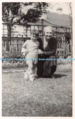 R420548 Eine Frau mit einem Schal um den Kopf und einem kleinen Kind im Garten