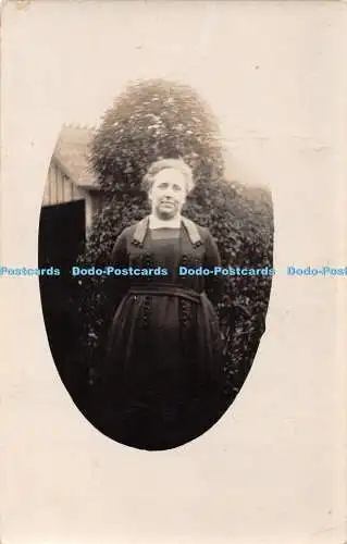 R444548 Eine alte Frau steht im Garten Postkarte