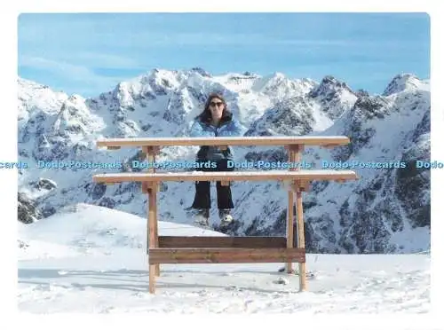 D267206 Frau sitzt auf einer Bank Snowy Mountains im Hintergrund Touchnote