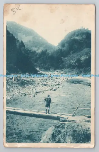 R801267 Person steht auf einer schmalen Holzbrücke über einen flachen Fluss bewaldet