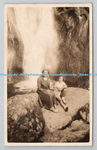 R801391 Frau und Kinder sitzen auf den Felsen neben Wasserfall L T K