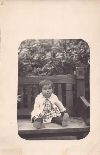 A090 Passepartout 1925 Kleines Mädchen im karierten Kleid sitzt auf Bank RPPC Postkarte