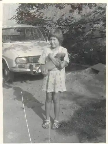 Anonymous persons souvenir photo Romania girl posing with puppy dog pet near Dacia car