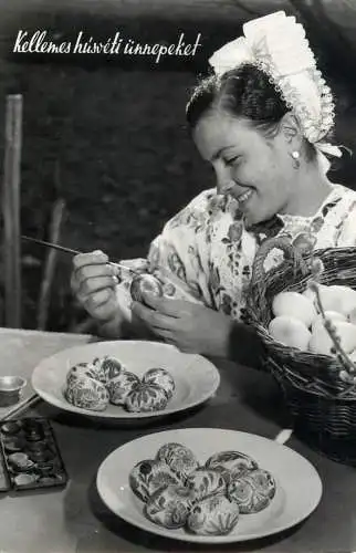 Greetings woman in traditional costumes painting eggs for the Holiday of Easter