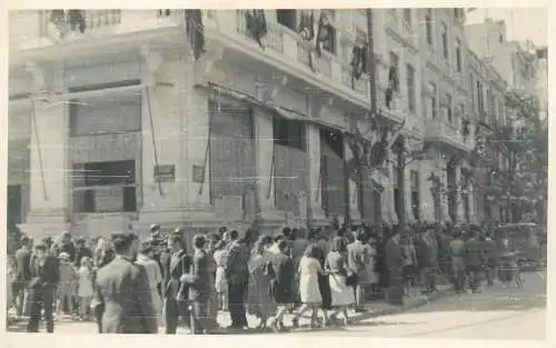 Photo postcard showing a busy scene full of pedestrians to identify