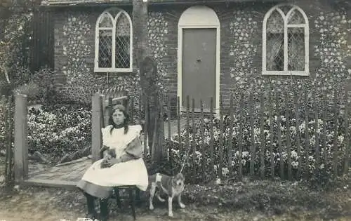 Postcard young girl sitting on chair in front of the house dog vintage clothing