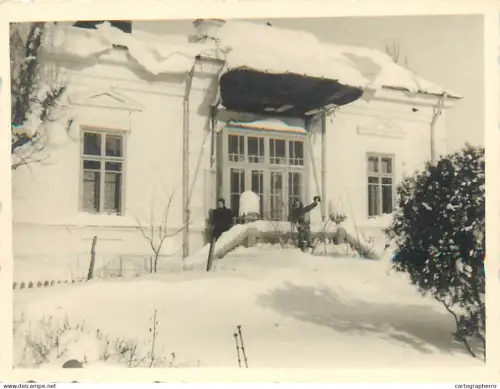 Anonymous persons in front of a house in snowy winter Romania