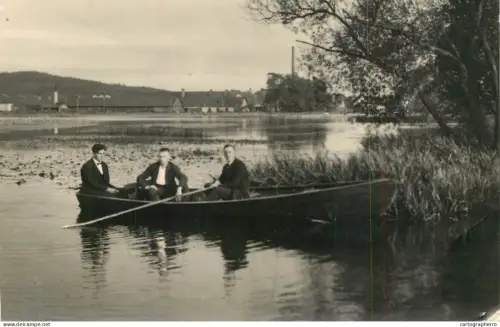 A5974 Photographic postcard showing a moment in time from the early 20th century featuring three men in a boat on a lake