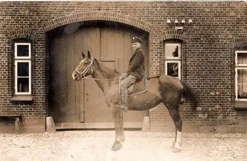 [Echtfotokarte schwarz/weiß] Junger Mann mit Pferd vor Ziegelgebäude – Echtfoto ca. 1910–1914. 