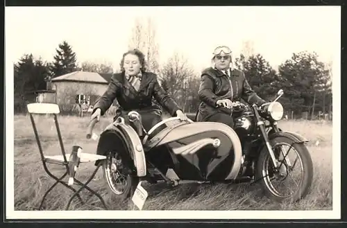 Foto-AK Motorrad Triumph TWN mit Beiwagen, Liebespaar fährt Motorrad und stösst eine Flasche vom Stuhl