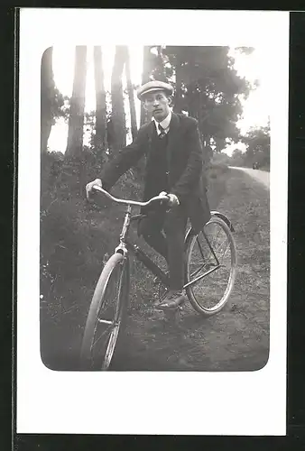 Foto-AK Junger Mann mit Schiebermütze auf Fahrrad