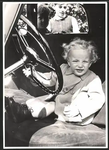 Fotografie Auto, niedliches Kind sitzt am Steuer eines PKW's