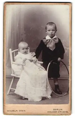 Fotografie Wilhelm Stein, Berlin, Portrait Knabe mit Holzreifen und Säugling in Taufkleid