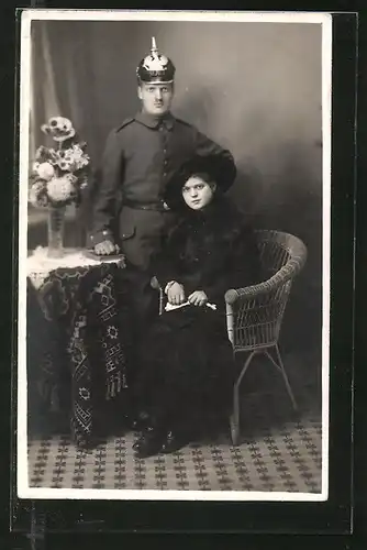 Foto-AK Feldgrauer mit Pickelhaube und junge Dame in schwarz