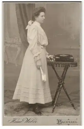 Fotografie Heinrich Weber, Backnang, junge Frau im weissen Kleid mit Fächer, Fotoalbum liegt auf dem Tisch
