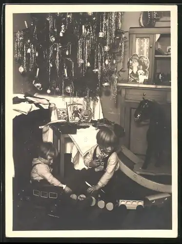 Fotografie Weihnachten, Kinder spielen mit Spielzeug-Eisenbahn und Blechauto unter dem Weihnachtsbaum