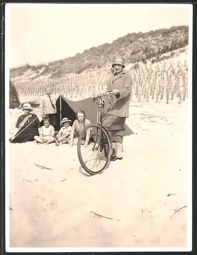 Fotografie Frau mit Fahrrad am Strand, Kinder sitzen vor einem Zelt