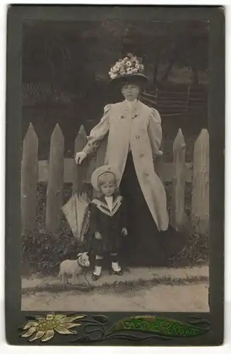 Fotografie Fotograf & Ort unbekannt, Dame mit modischem Hut nebst Tochter in Marine-Uniform, Spielzeug-Schaf