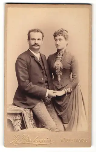 Fotografie Rud. Bradengeier, Düsseldorf, Ehepaar zünftig gekleidet hält Händchen