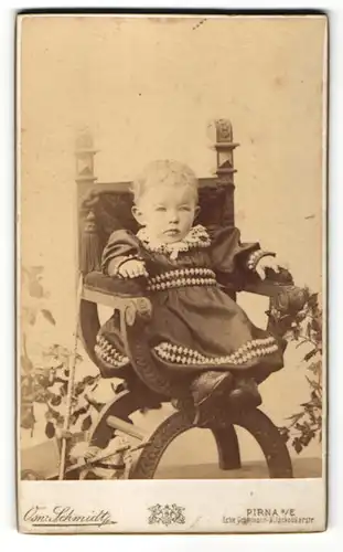 Fotografie Osw. Schmidt, Pirna, Baby im Kleid auf Sessel sitzend