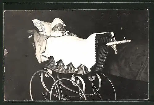 Foto-AK Baby mit Mütze liegt in einem Kinderwagen