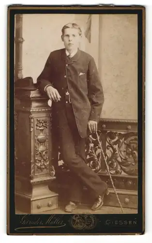 Fotografie Gebrüder Müller, Giessen, Portrait halbwüchsiger Knabe in Anzug mit Gehstock
