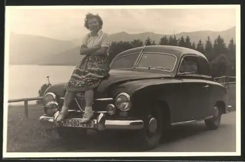 Fotografie Auto Borgward, junge Frau auf Motorhaube posierend, Tegernsee im Hintergrund