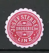 Präge-Reklamemarke Drogerie Josef Sterrer zu Linz, rot