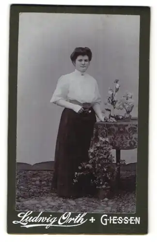 Fotografie Ludwig Orth, Giessen, hübsche Dame mit Blumen am Tisch stehend