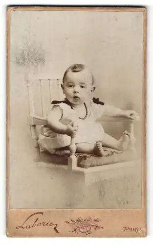 Fotografie Laborie, Paris, niedliches Baby im weissen Kleid mit Perlenhalskette