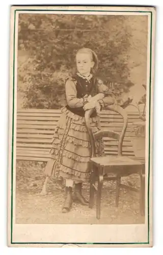 Fotografie Fotograf & Ort unbekannt, junges Mädchen im hübschen Rüschenkleid am Stuhl stehend