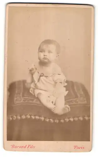 Fotografie Bacard Fils, Paris, niedliches Baby im weissen Kleid auf Kissen sitzend