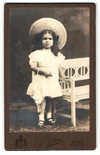 Fotografie F. Erben, Graz, kleines dunkelhaariges Mädchen mit grossem Hut und Tasche