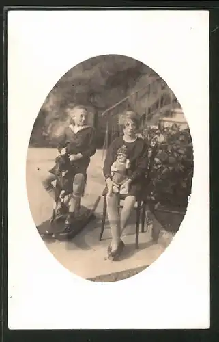 AK Junge auf einem Schaukelpferd und Mädchen mit Puppe auf dem Schoss