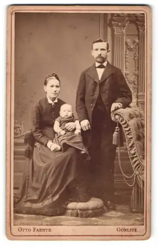 Fotografie Otto Faehte, Görlitz, hübsches junges Paar mit niedlichem Baby im edler Kleidung