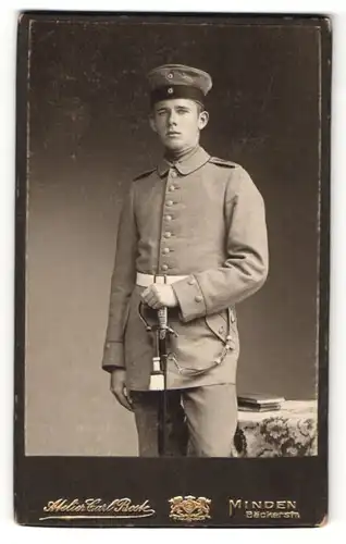 Fotografie Carl Beck, Minden, junger Soldat in Uniform mit Schirmmütze und Schwert