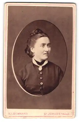 Fotografie H. Leonhard, St. Johann / Saar, Portrait hübsche Dame mit Flechtfrisur und Brosche