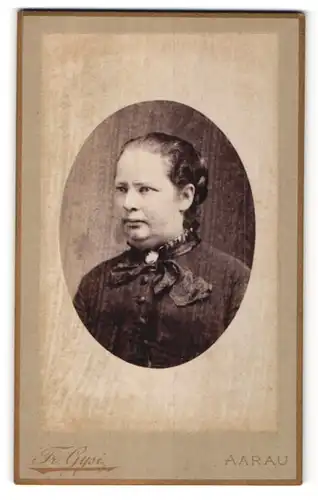 Fotografie Fr. Gysi, Aarau, Portrait hübsche Dame mit Flechtfrisur und Brosche am Kragen