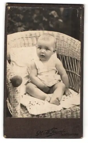 Fotografie Ph. & W. Freund, Schlüchtern, niedliches Baby im Korbsessel sitzend