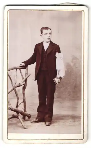 Fotografie Henry, Ort unbekannt, frecher dunkelhaariger Bube im schwarzen Anzug mit Schleife und Buch