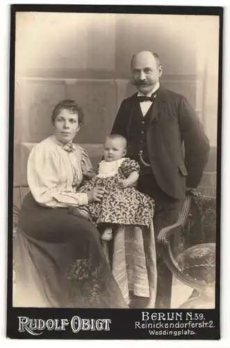 Fotografie Rudolf Obigt, Berlin-N, Portrait bürgerliches Paar mit Kleinkind