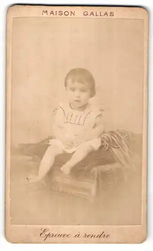 Fotografie Maison Gallas, Ort unbekannt, niedliches kleines Mädchen mit brünetten Haaren auf Kissen sitzend