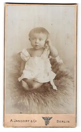 Fotografie A. Jandorf & Co., Berlin, Portrait Kleinkind im Hemdchen auf einem Fell