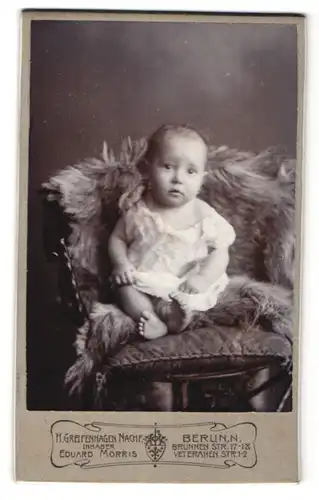 Fotografie H. Greifenhagen Nachf., Berlin, Portrait niedliches Baby auf einem Fell sitzend